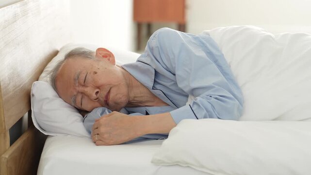 ベッドで休む体調不良の高齢者の男性