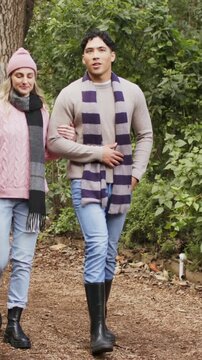 Vertical video: Walking couple after arm link, strolling park path sharing wearing scarves beanie