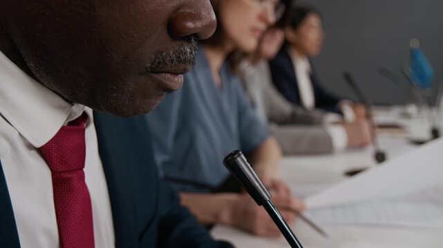 Black politician speaking into microphone at international summit with diverse delegates. Footage serves well for global relations and leadership training videos close up shot