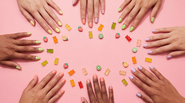 Colorful gummy nail art flat lay with hands and candy charms