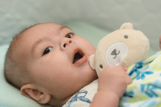 beb&eacute; latino jugando con su juguete de apego emocional en su cuna