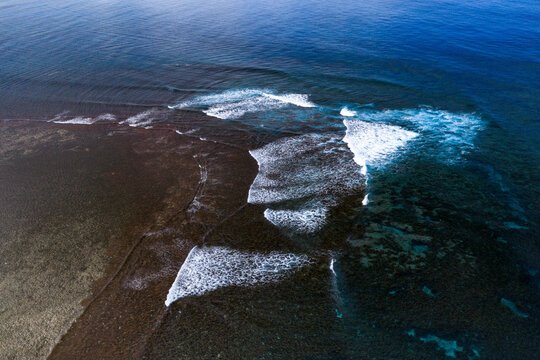 Aerial view of breaking waves over a coral reef and turquoise ocean waters at Siargao Island in General Luna, Caraga, Philippines.