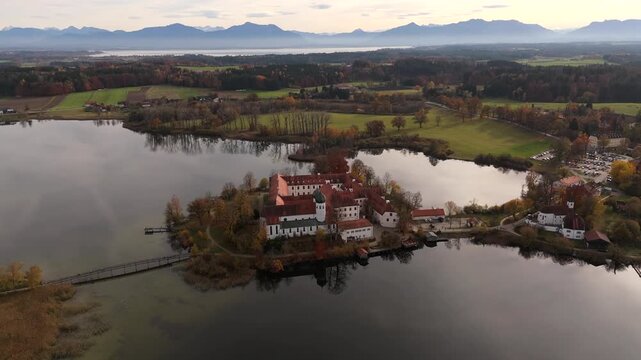 Drone video showing Seeon Abbey, tranquil lake reflections, and alpine landscape in Chiemgau, Bavaria, Germany. Luftaufnahme Kloster Seeon in Seeon-Seebruck, Oberbayern, Deutschland, auf Halbinsel 