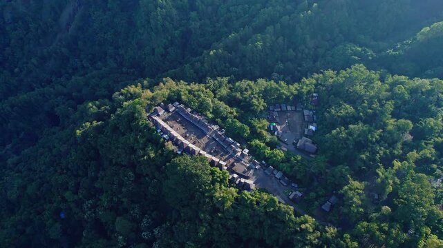 Aerial view of Bena Traditional Village with its iconic thatched roofs surrounded by dense tropical forest in the mountains Kecamatan Jerebuu, Nusa Tenggara Timur, Indonesia.