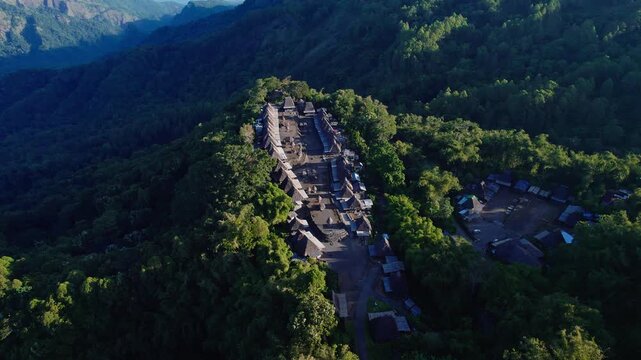 Aerial view of Bena Traditional Village with its iconic thatched roofs situated on a lush green mountain ridge in Kecamatan Jerebuu, Nusa Tenggara Timur, Indonesia.
