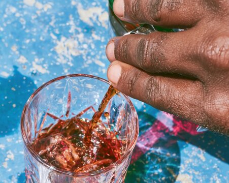Overhead view of a hand pouring aromatic bitters into a crystal negroni cocktail, featuring cold condensation and rich textures for mixology education