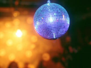 Obraz premium Purple mirrored disco ball hanging in a fiery party setting with glowing amber light for festive celebration and nightlife events