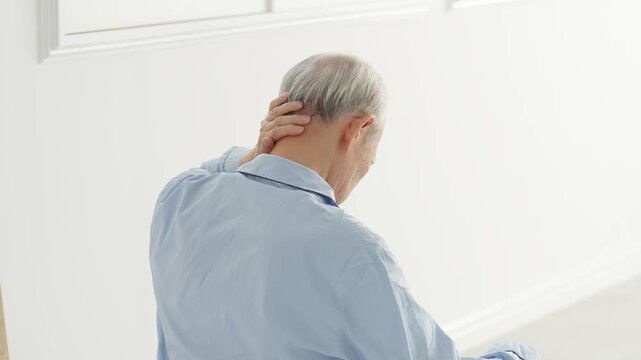 頭を押さえる体調不良の高齢者の男性