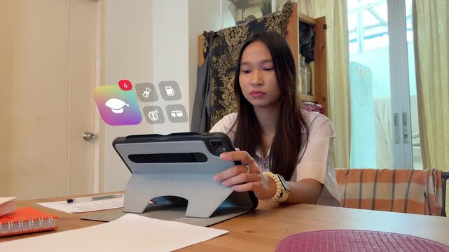 A young Southeast Asian student looks at her tablet device, displaying a vibrant rainbow gradient graduation cap icon tracked in 3D, alongside virtual brain, school bus, and textbook notification indi