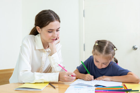 Teacher assisting young student with drawing and learning activity in classroom. Creative education, child development, personalized learning, and academic support concept.