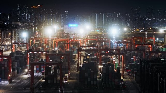 Cargo Cranes Loading And Unloading Containers On Trucks In A Busy Illuminated Container Terminal At Night With The Hong Kong Skyline In The Background. International Trade, Logistics Hub