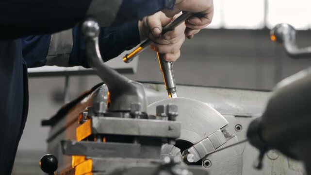 Skilled machinist adjusting industrial lathe machine in manufacturing workshop. Precision metalworking, machine setup and engineering production process.