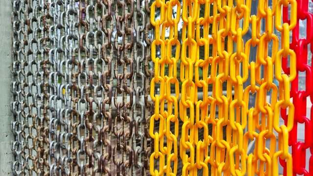 Rusty metal and bright yellow and red plastic chains hanging side by side