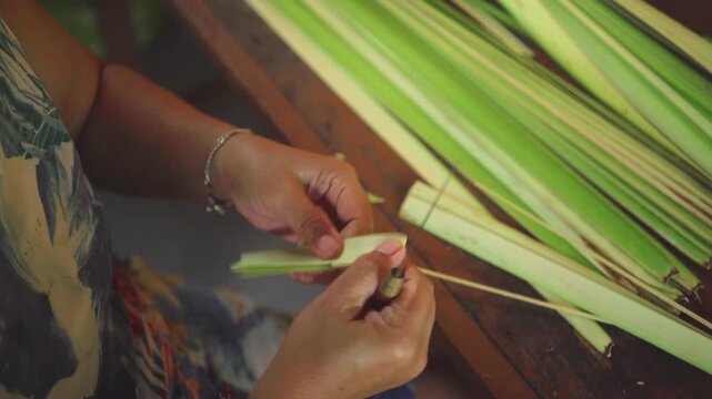 Close up of Balinese woman cutting palm leaves to make canang sari, a traditional Balinese Hindu offerings. Horizontal 4K footage. Religion concept