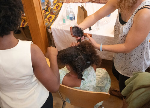 Professional hairdresser working on a client's afro-textured hair, preparing it for a style