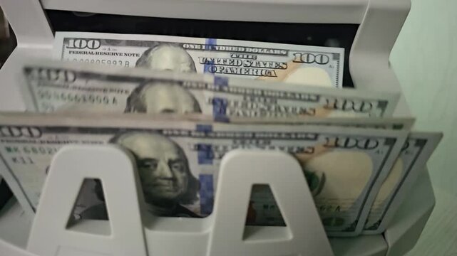 Money counting machine in action shows hundreds of dollar bills being processed in a fast and efficient manner