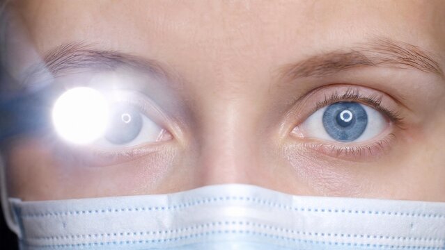 Ophthalmologist Examining Blue Eyes with Penlight Close-up
