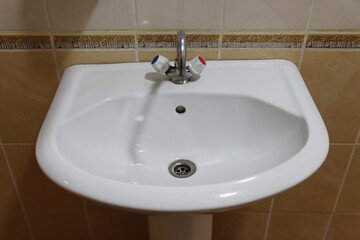 Fototapeta premium A white sink with a silver faucet and a drain