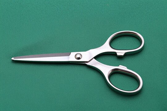 A pair of scissors sitting on top of a green cloth