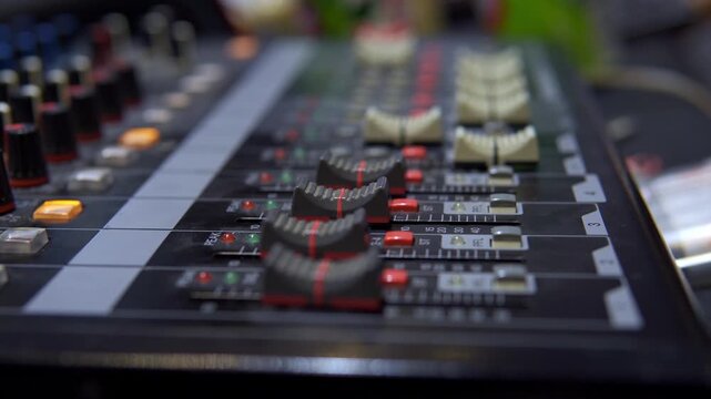 Professional sound engineer adjusting audio mixing console faders