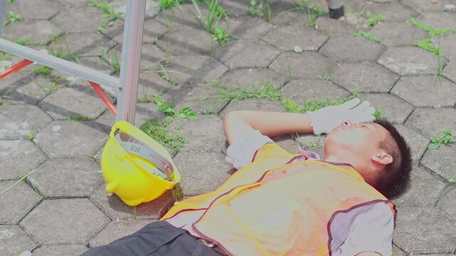 Construction worker lying unconscious on the ground following a dangerous fall from a ladder.