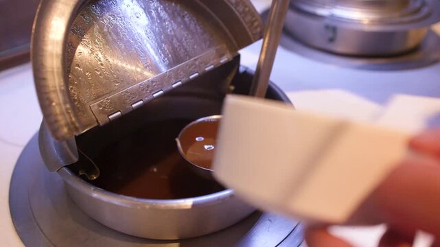 Hand Pouring Hot Asian Soup with Enoki Mushrooms into a Bowl