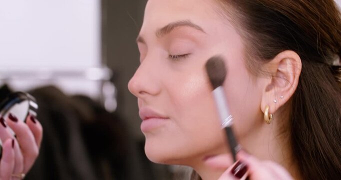 Skin treatment. Facial procedure. Female professional visagiste using brush applying cosmetic powder for makeup in beauty salon.