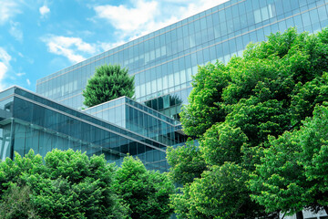 Eco-friendly building in the modern city. Sustainable glass office building with trees for reducing heat and carbon dioxide. Office building with green environment. Corporate building reduce CO2. © Fahroni