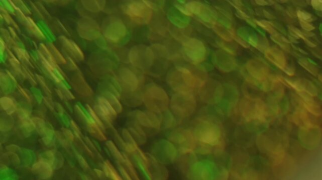Defocused twinkle particles. Blurred gleam. Duplicated lens flare prism stroboscopic color rotation. Shiny bokeh light leak green yellow abstract background.