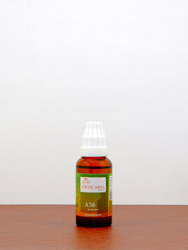 Allen - Urticaria A56 dropper bottle containing homeopathic remedy for skin hives with a white plastic cap and a green label standing upright on a smooth wooden surface on white background