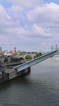 Aerial view of the Erasmusbrug bridge with its bascule section raised over the Nieuwe Maas river with the city skyline in the background in Rotterdam, Zuid-Holland, Netherlands.