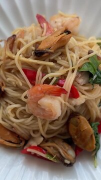 Spicy seafood spaghetti is served on a white plate.