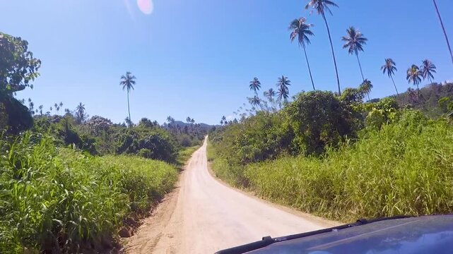 Four wheel drive truck on rough, bumpy gravel road lined by lush green landscape on tropical island of Bougainville, Papua New Guinea