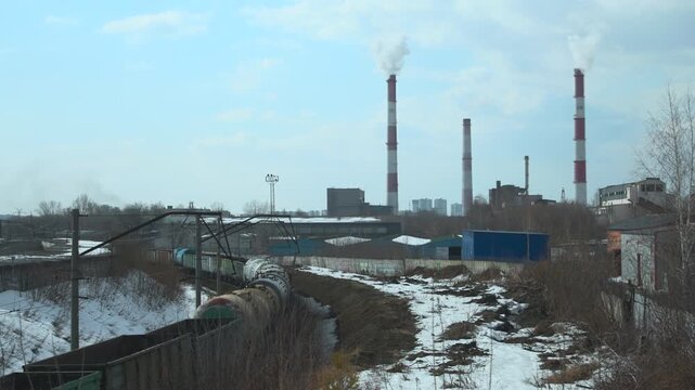 Industrial plant with smoking chimneys in a snowy urban landscape