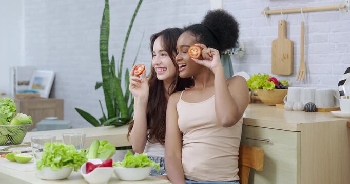 asian african american teenage female smiling slowmotion holding tomato slices enjoying healthy salad prep expressing joy promoting friendship wellness beauty skincare clean eating lifestyle fun