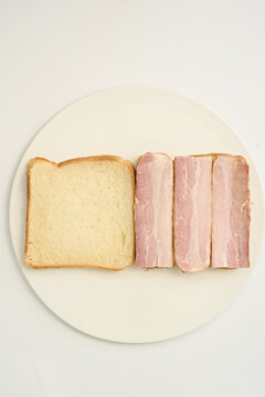tep 13: Placing crispy fried bacon slices on one side of white bread on a ceramic plate