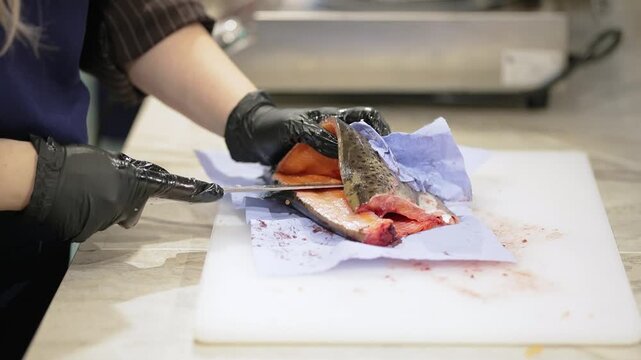 Cutting red fish with a knife at a master class. Very soft focus