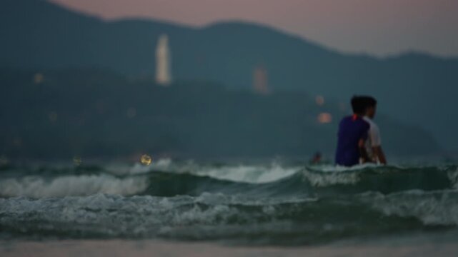 People swim in Danang sea, Lady Buddha statue and Linh Ung Pagoda above waves and tourists in Da Nang, Coastal view of Son Tra Peninsula with Buddhist landmark, mountains and ocean shoreline 4k