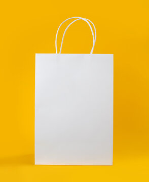 Blank White Paper Shopping Bag Mockup with Handles Isolated on Yellow Background