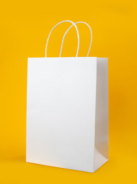 Blank White Paper Shopping Bag Mockup with Handles Isolated on Yellow Background