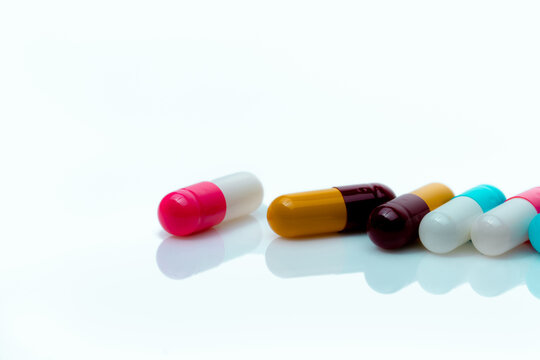 Multi-color antibiotic capsule pills on white background. Antibiotic drug resistance. Prescription drugs. Polypharmacy concept. Pharmacy drugstore product. Pharmaceutical industry. Capsule manufacture