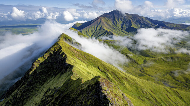 Dramatic mountain peaks surrounded by clouds and lush green landscapes create breathtaking view of nature beauty