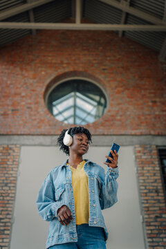 Young black woman listening to music using smartphone