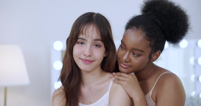 close moment between multiracial teen models gently posing together showing soft skin glowing smile cozy indoor lighting skincare elegance bonding wellness selfcare slowmotion concept