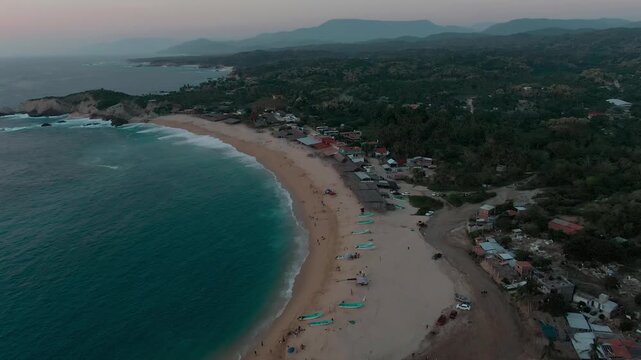 Playa El Faro with its wide sandy shoreline, turquoise Pacific waters, fishing boats, beachfront palapas, and coastal village near Faro de Bucerias, Michoacan, Mexico.