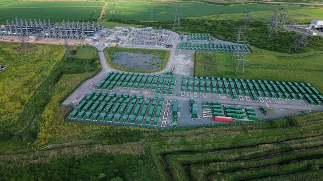 Aerial view of Tilbury Battery Energy Storage System and Thurrock Flexible Generation Project with rows of green containers and power pylons in Tilbury, England, United Kingdom.