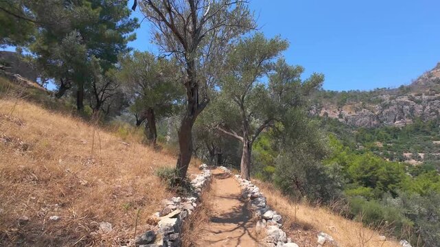 A walking path in the ancient city of Amos in Turunc, Marmaris. Hiking in the mountains, among olive trees. 4k horizontal video. Adventure, outdoor sports concept. No people, nobody.