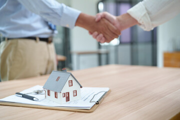 Naklejka na ściany i meble Real estate transaction with handshake and miniature house model