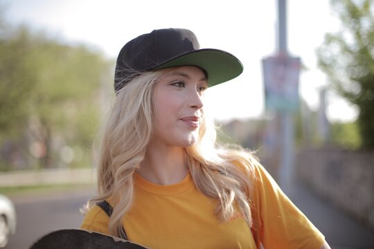 Young blonde woman with skateboard smiling outside