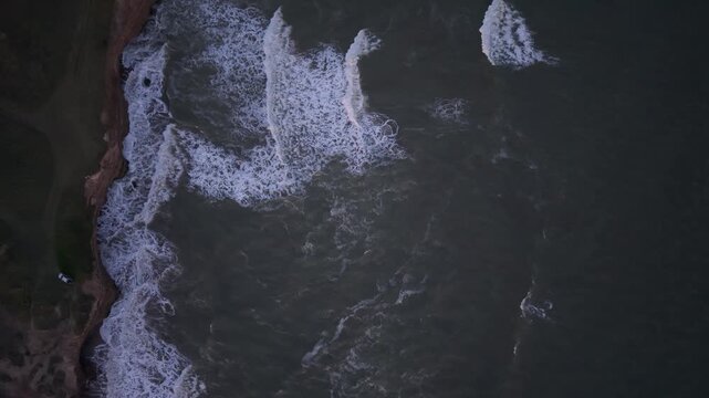 Orilla del mar con olas chocando contra acantilado, naturaleza costera vista cenital a&eacute;rea
